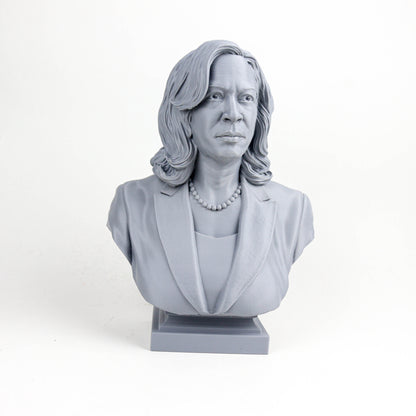 A gray bust sculpture of a woman with long hair and a pearl necklace, wearing a jacket.