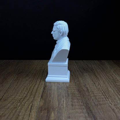 A white bust of a man is sitting on a wooden surface against a dark background.