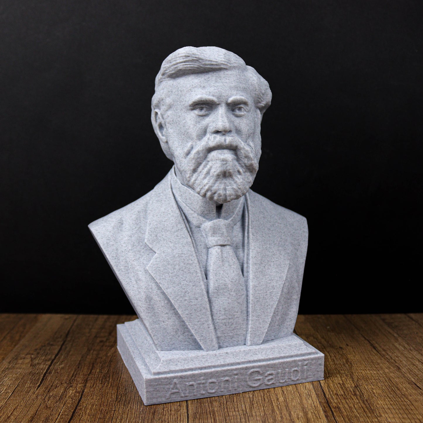 A bust of a bearded man wearing a suit and tie, sitting on a wooden surface.