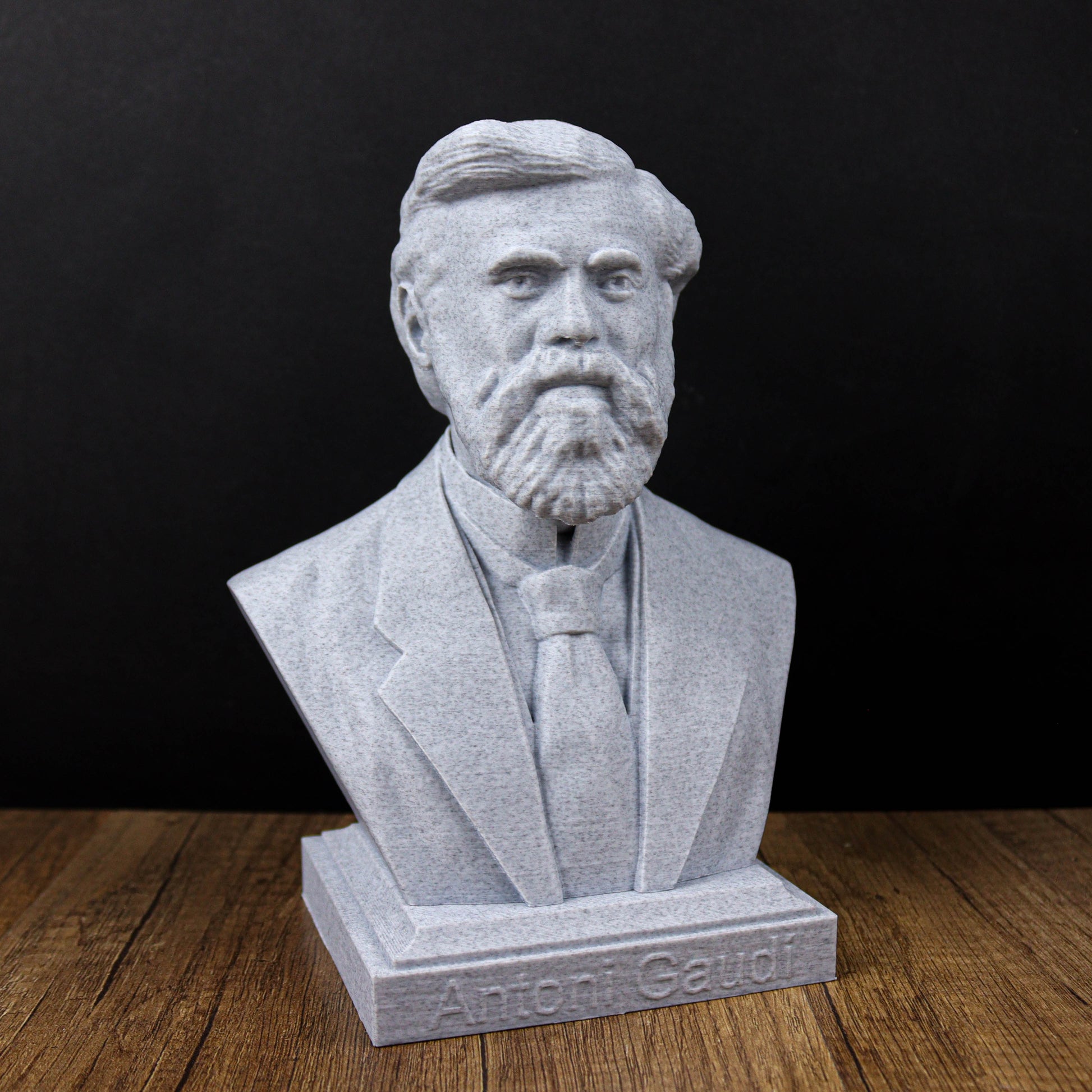A bust of a bearded man wearing a suit and tie, sitting on a wooden surface.