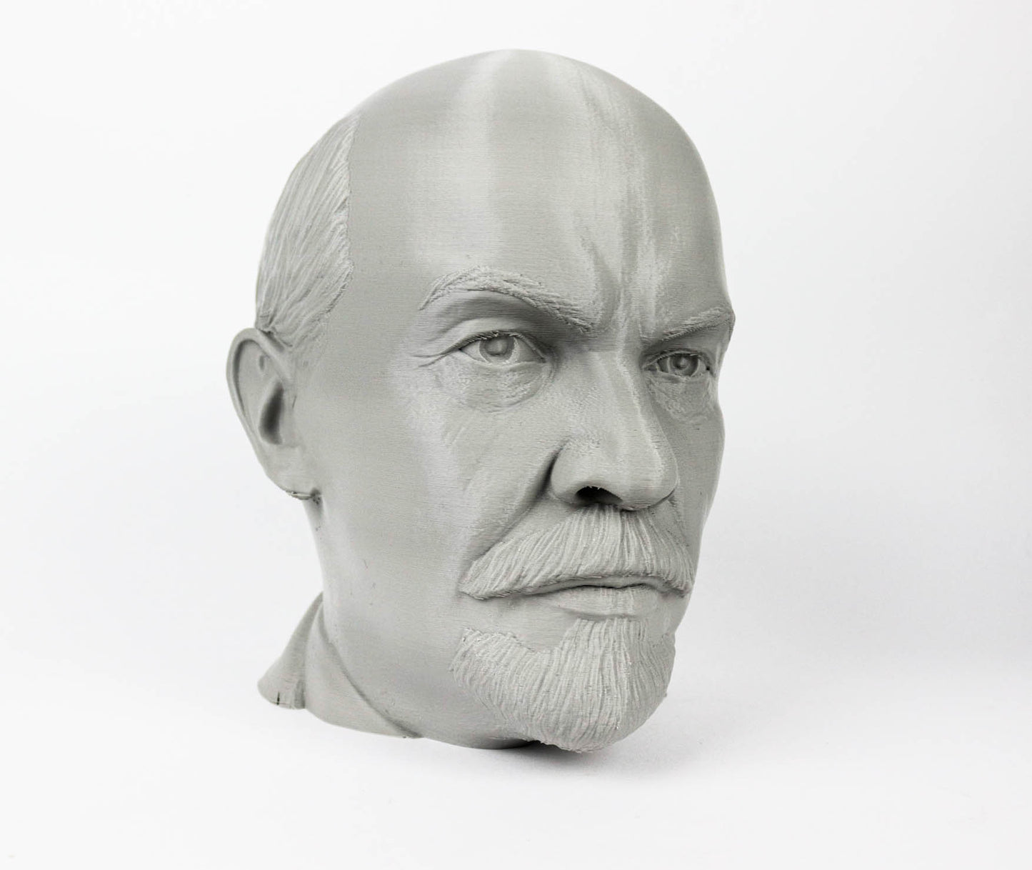 A gray bust of a man's head, with a serious expression and a mustache.