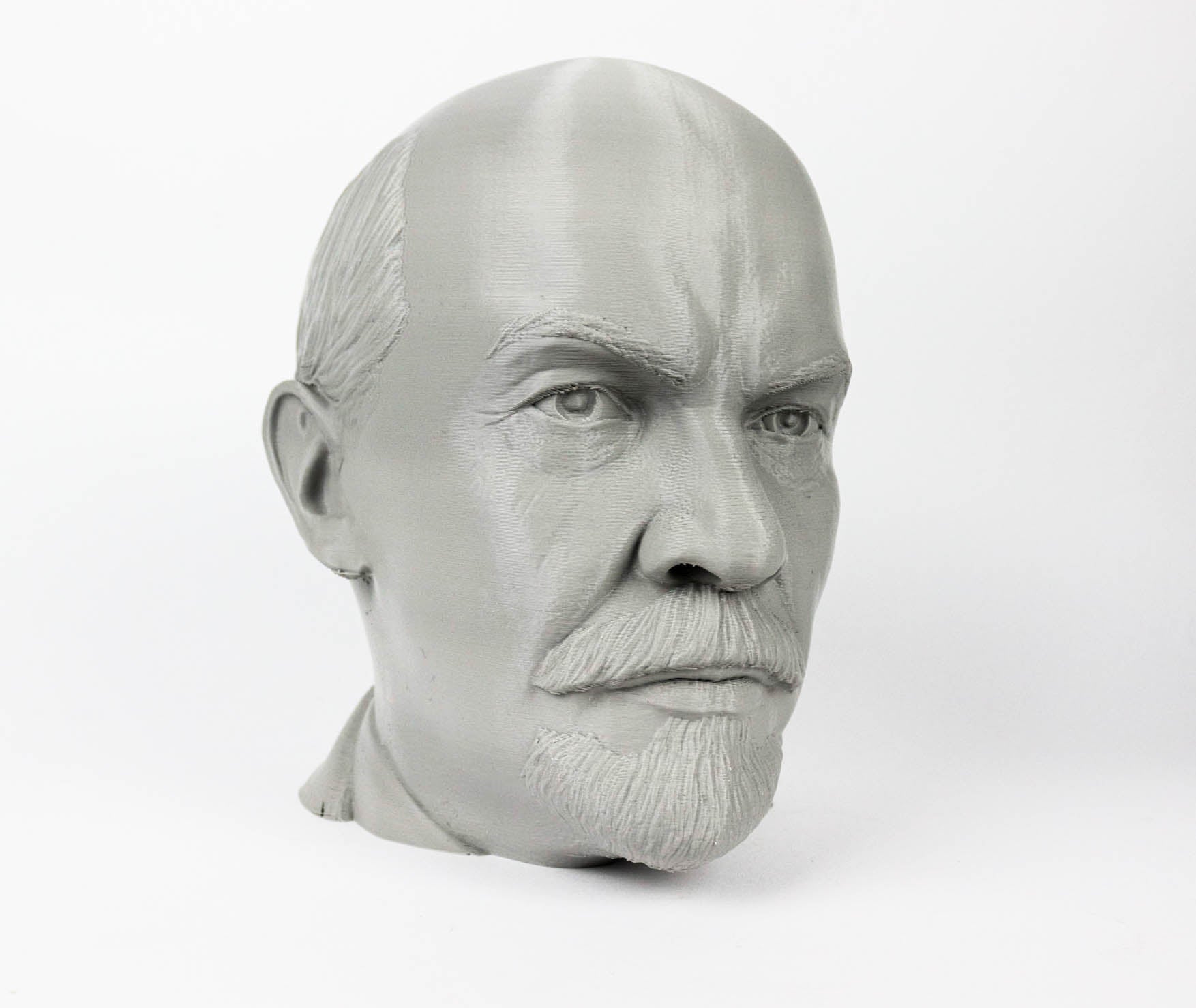 A gray bust of a man's head, with a serious expression and a mustache.