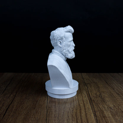 A white bust of a bearded man is displayed on a wooden surface against a dark background.