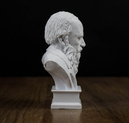 A white bust of a bearded man is displayed on a wooden surface against a black background.