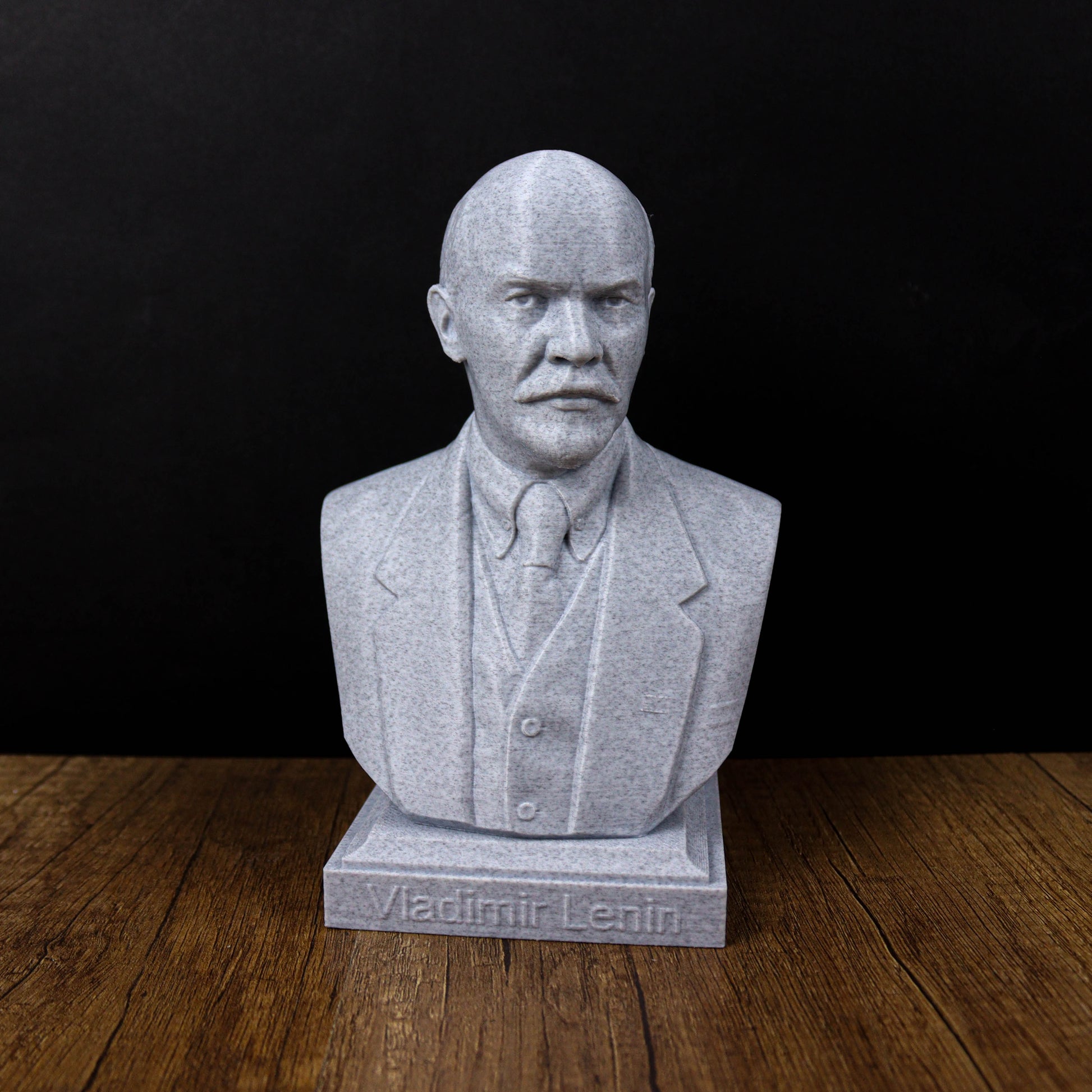 A bust of Vladimir Lenin, a prominent Russian political leader, is displayed on a wooden surface against a black background.