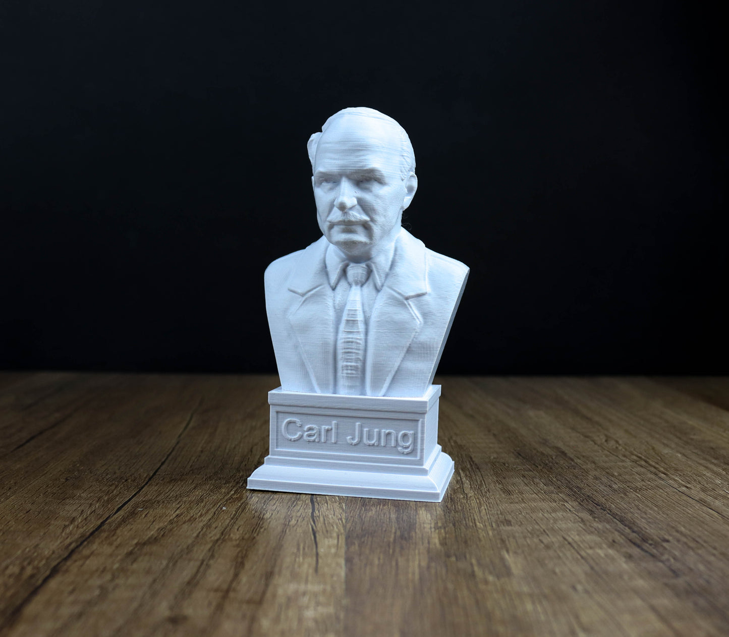 A white bust of a man wearing a suit and tie, with the name "Carl Jung" engraved on a pedestal below the bust.