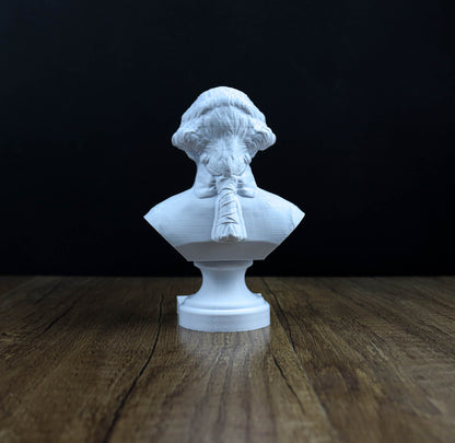 A white bust of a person is displayed on a wooden surface against a dark background.