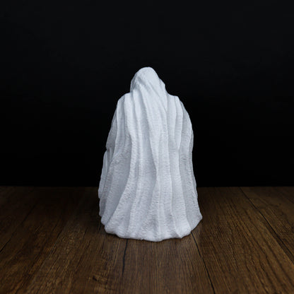 A white, flowing ghost-like figure sits on a wooden surface against a dark background.