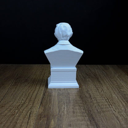 A white bust of a person sitting on a wooden surface against a dark background.