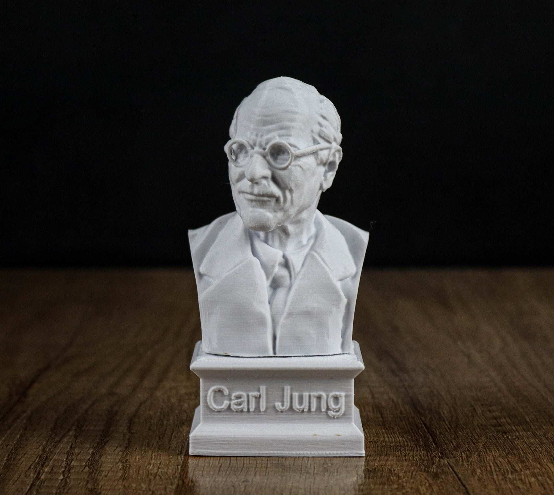 A white bust of a man wearing glasses and a suit, with the name "Carl Jung" engraved on the base.