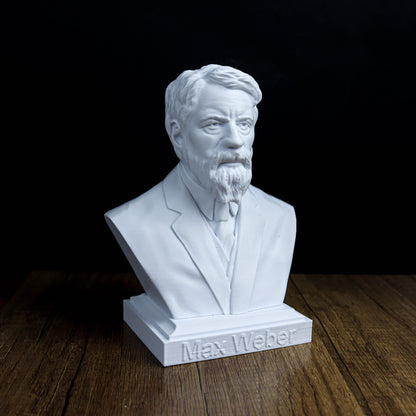 A white bust of a bearded man wearing a suit, sitting on a wooden surface.