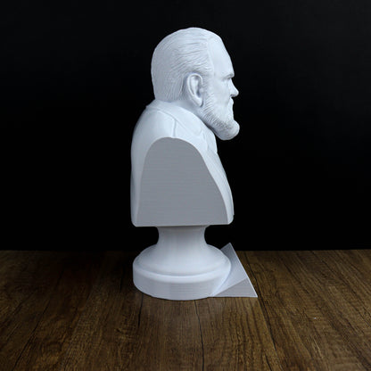 A white bust of a man is displayed on a wooden surface against a black background.