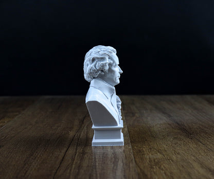 A white bust of a man is displayed on a wooden surface against a dark background.