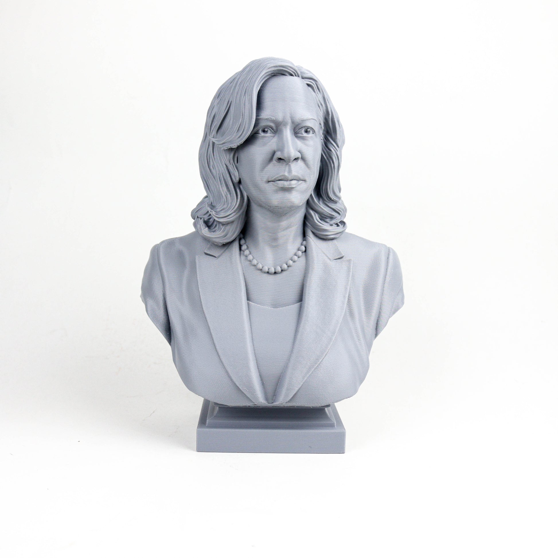 A gray bust sculpture of a woman with long hair and a pearl necklace, wearing a jacket.