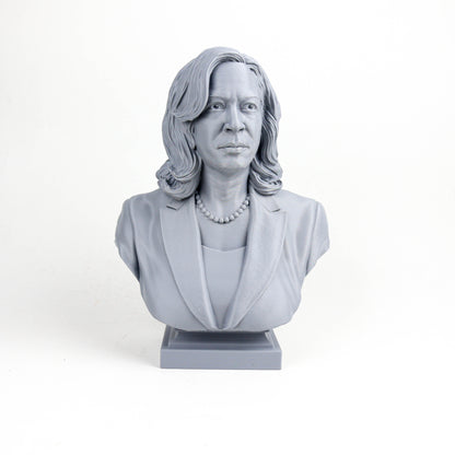 A gray bust sculpture of a woman with long hair and a pearl necklace, wearing a jacket.