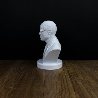 A white bust of a person is displayed on a wooden surface against a black background.