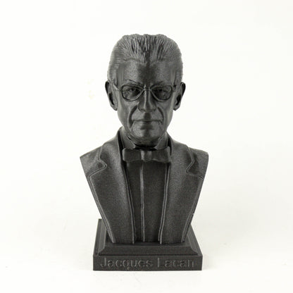 A black bust sculpture of a man wearing a suit and bow tie, with the name "Jacques Lacan" engraved on the base.