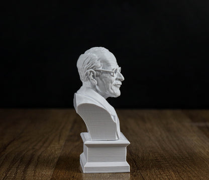 A white bust of a man's head is displayed on a wooden surface against a black background.