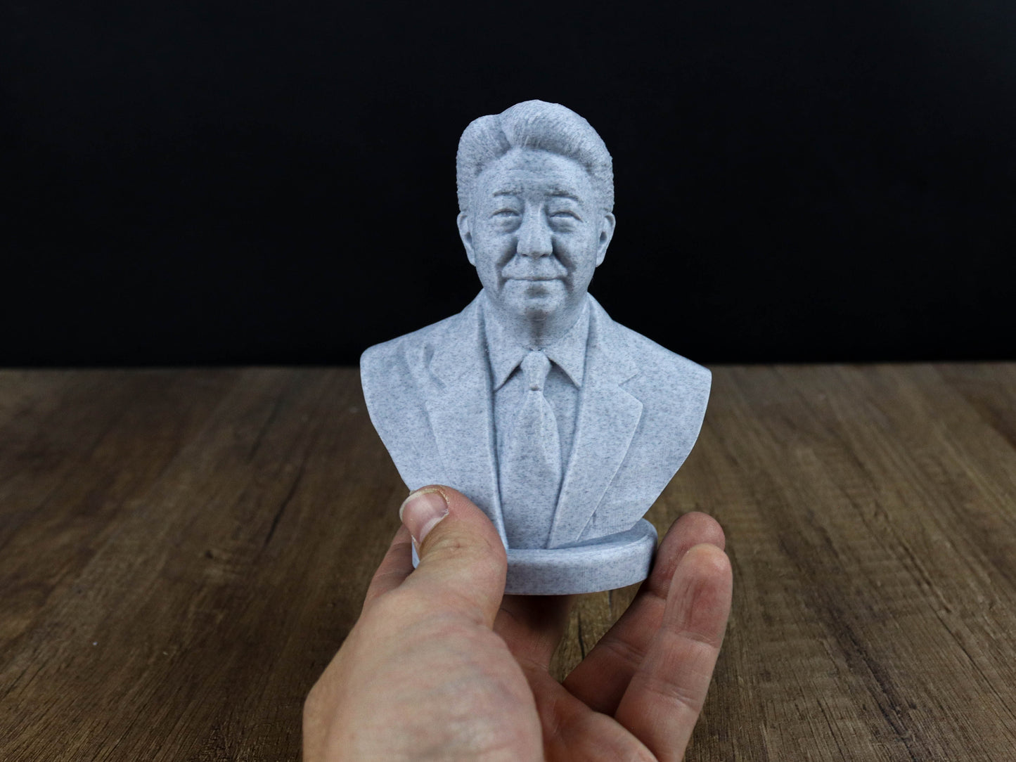 A hand is holding a small bust of a man in a suit, which appears to be a 3D printed object.