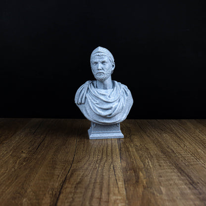 A small white bust of a man is displayed on a wooden surface against a black background.