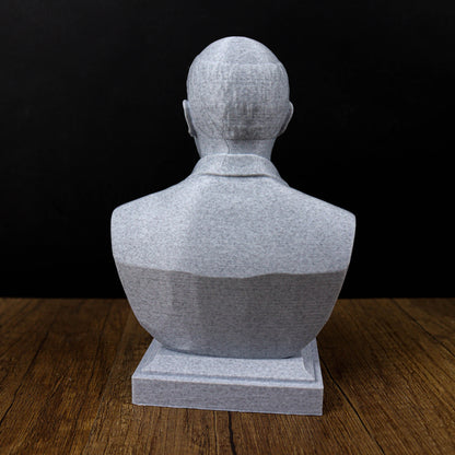 A gray stone bust sculpture of a person's head is displayed on a wooden surface against a black background.