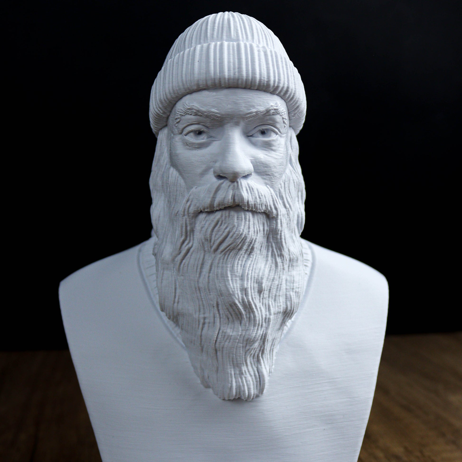 A white bust sculpture depicting a bearded man wearing a knit cap.